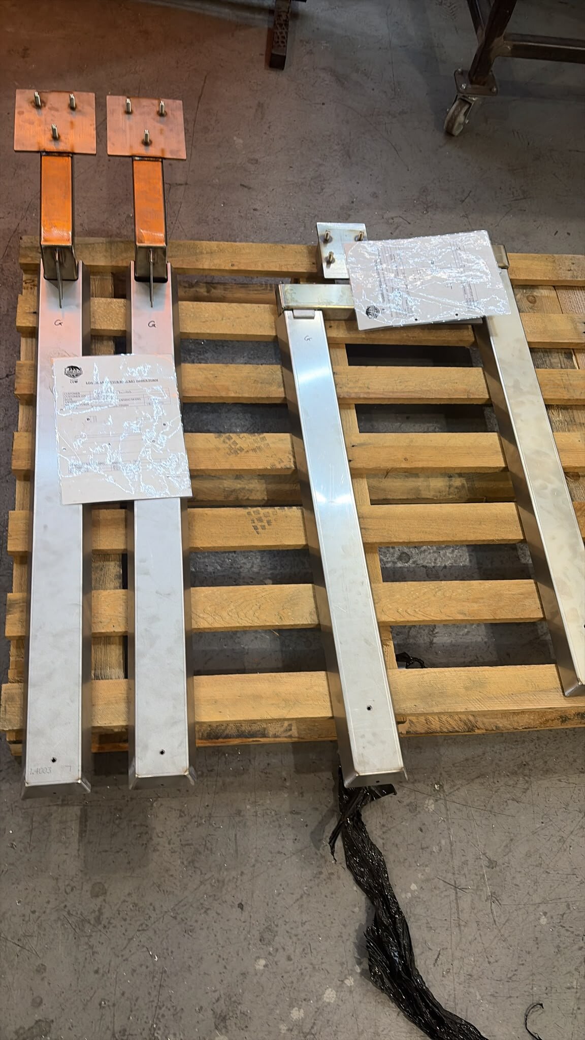 Custom LoadBear awning brackets on a pallet with drawings taped to the frames