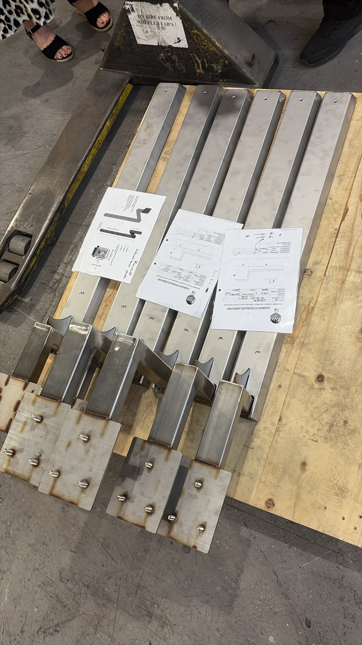Six LoadBear gutter brackets on a workshop pallet with order forms and drawings