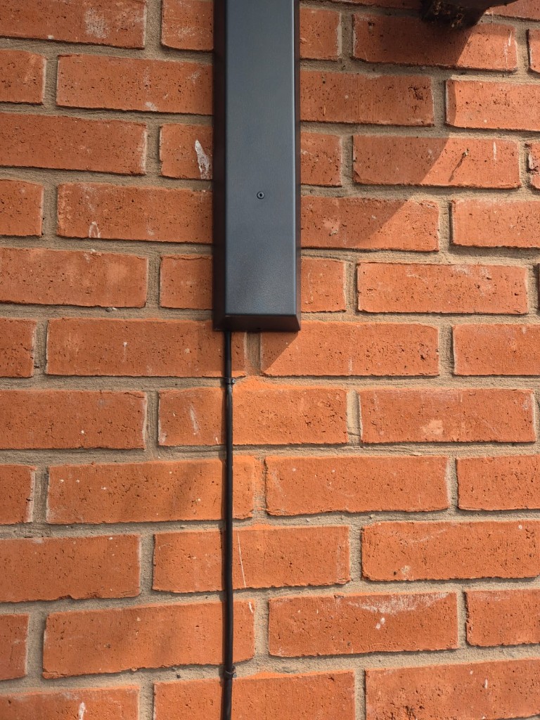 Anthracite awning bracket cover with a neatly routed power cable on a bungalow wall