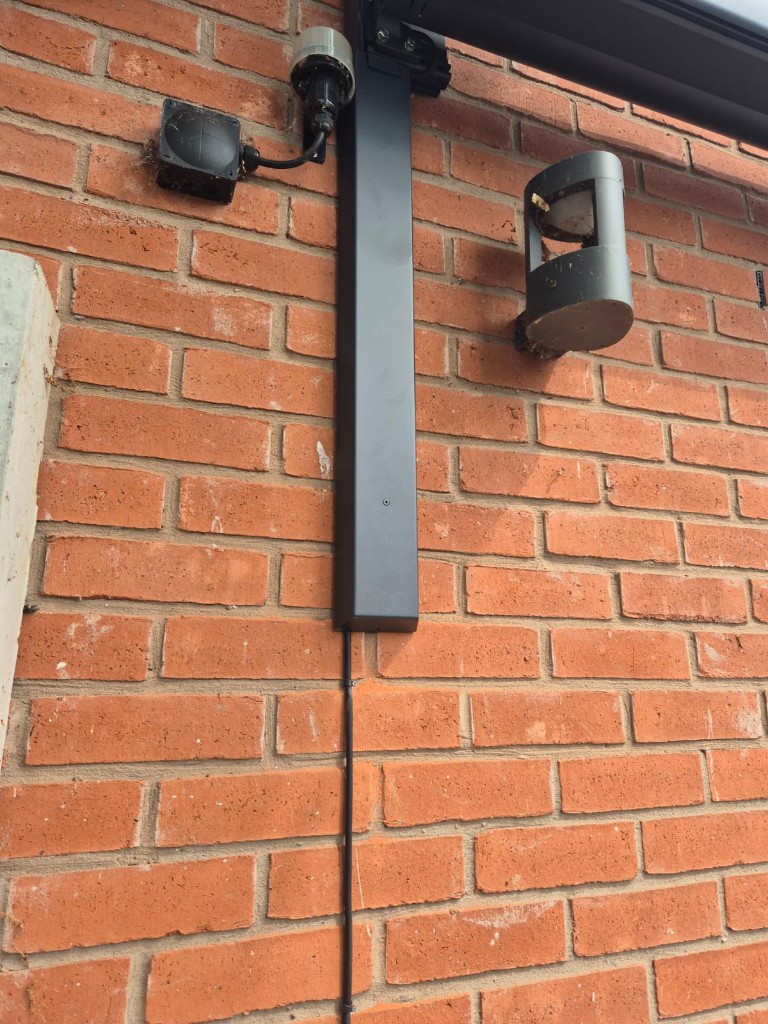 Left-side anthracite bracket supporting a cassette awning above a bungalow window