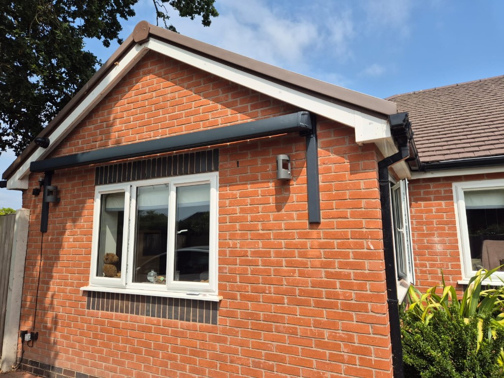 Angled view of a finished anthracite awning bracket installation on a red-brick bungalow