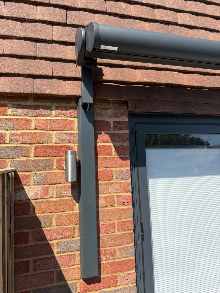 Close-up of an anthracite LoadBear vertical bracket supporting a BASE awning cassette