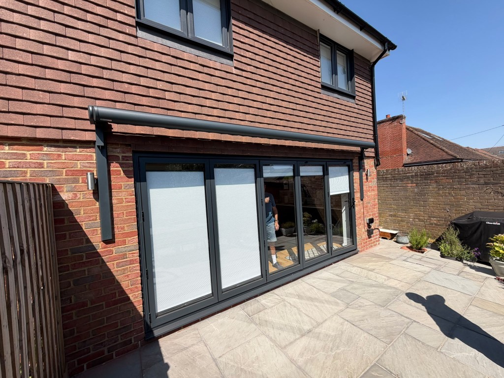 Anthracite BASE awning on two LoadBear vertical brackets above bi-fold patio doors