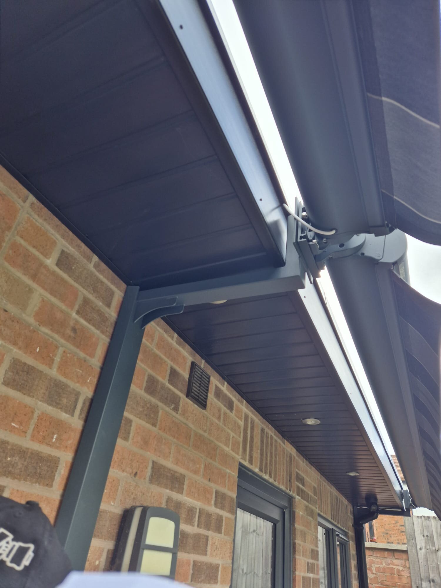 Low-angle view of a LoadBear gutter bracket upright on brick under recessed soffit lights