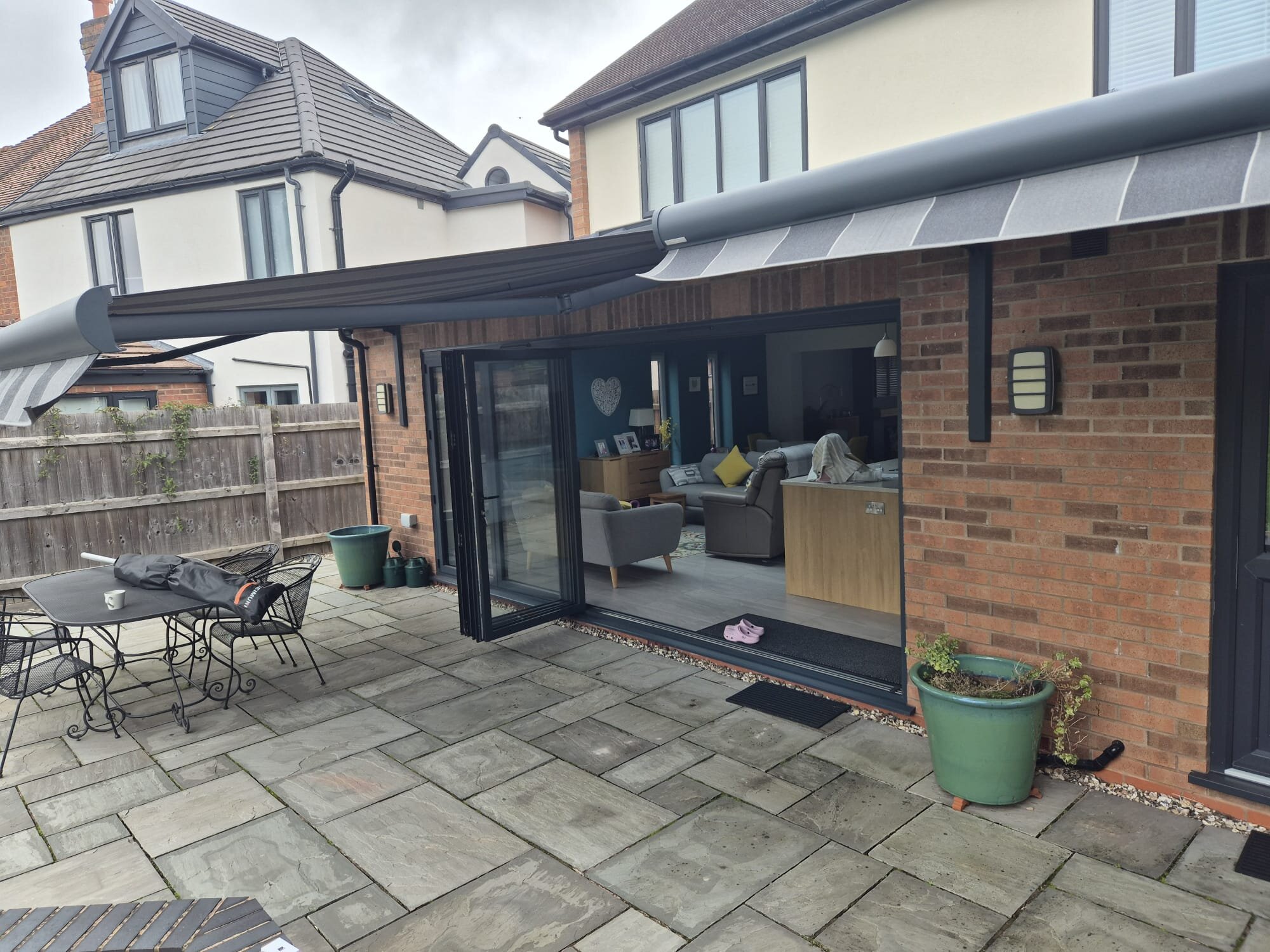 Twin patio awnings on LoadBear brackets above open bifold doors on red brick