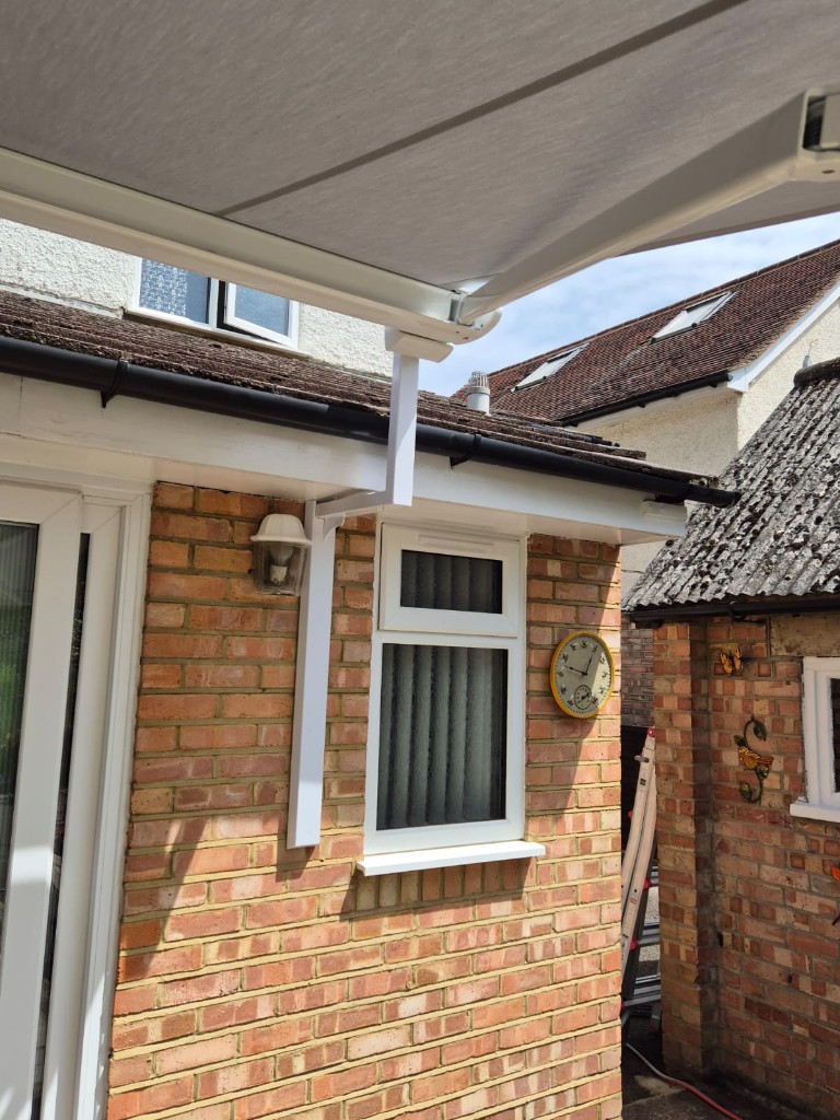 LoadBear gutter bracket between patio doors and window — colour-matched white upright on brick