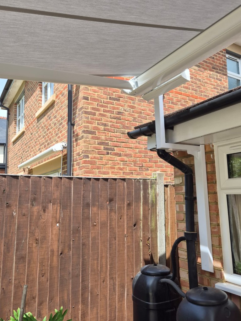 Side elevation awning on LoadBear gutter bracket beside a downpipe — discreet eaves-clearing mount
